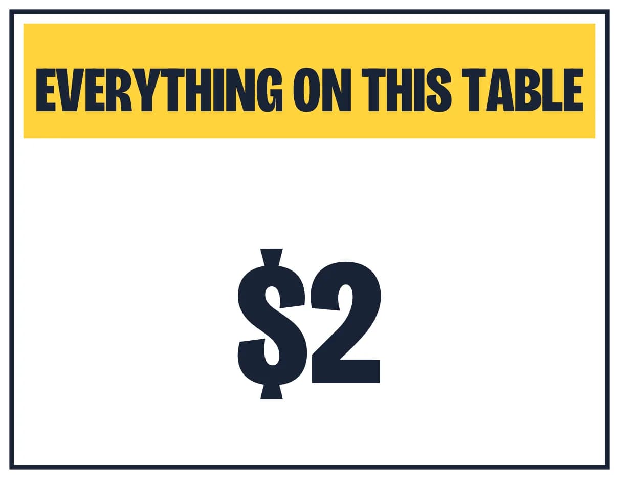 A sign with EVERYTHING ON THIS TABLE on a yellow band and $2 in very large letters below it.